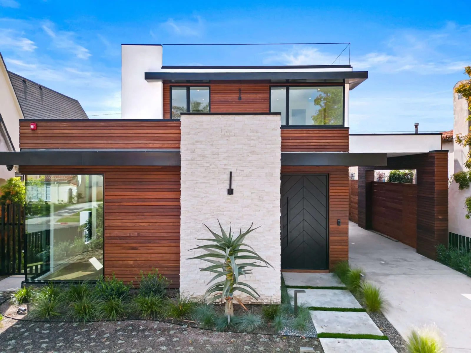 A completed luxury custom home in Los Angeles with cedar cladding and a stone entry, built by ArcLine Builders